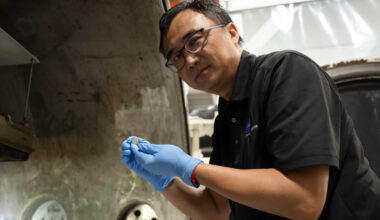 Yi Lin, SPEARS testing and research lead at NASA Langley, holds one of the small coin-cell batteries that had just undergone thermal vacuum testing.