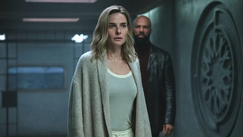 Rebecca Ferguson as Juliette Nichols standing in an empty hallway in front of Common as Robert Sims in Silo
