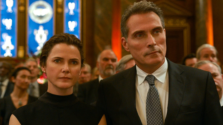 Keri Russell as Katherine Wyler and Rufus Sewell as Hal Wyler, sitting together in The Diplomat.