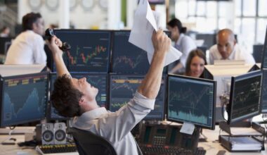 Stock trader celebrates with papers amid monitors displaying financial market charts.