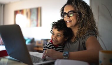 Parent hugging child and looking at laptop.