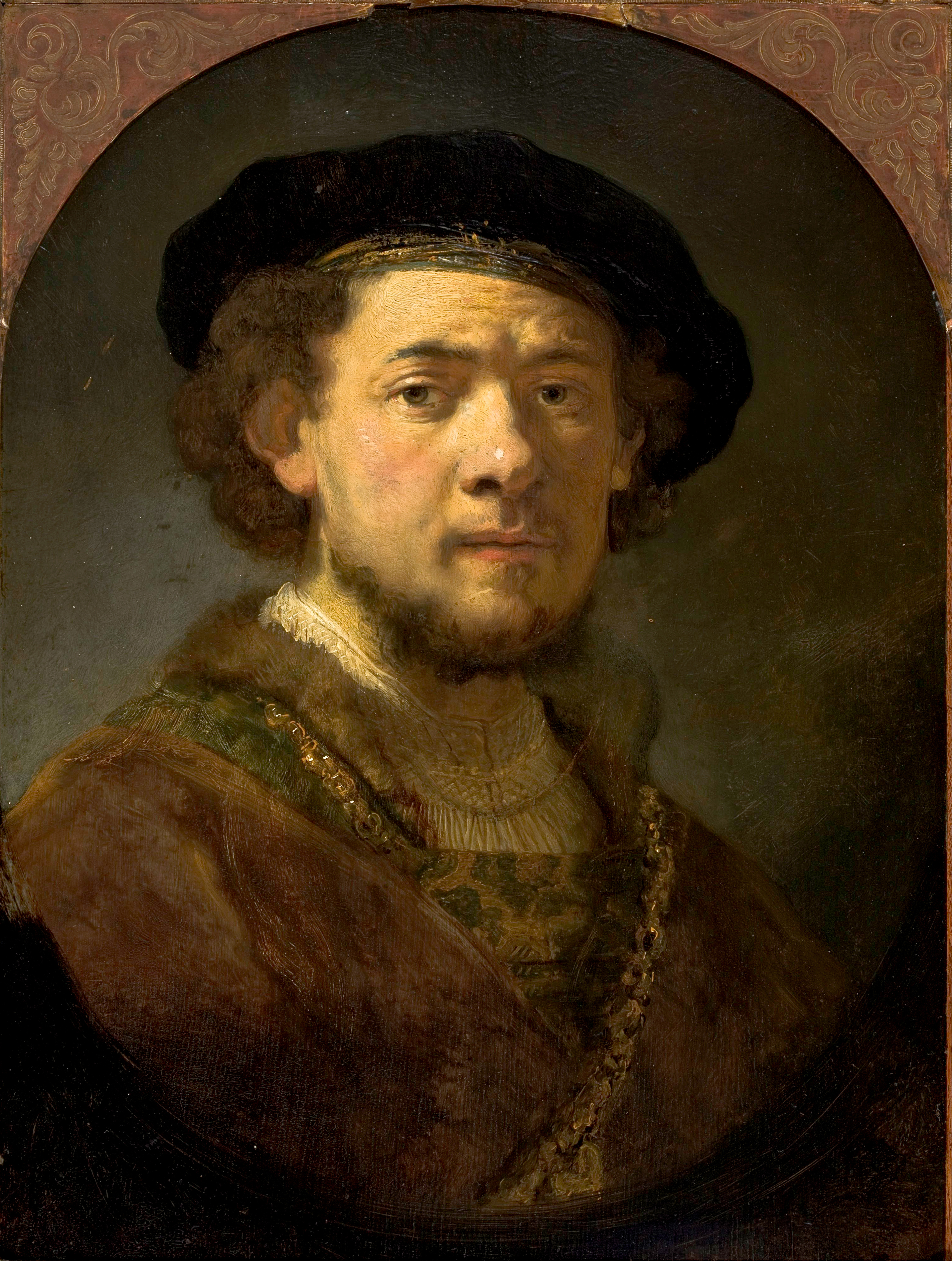 Portrait of a young man wearing a dark cap and gold chain.