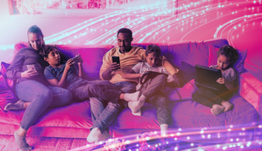 Family sitting on a couch browsing on their phones and tablets.