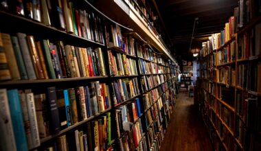 A narrow aisle lined with tall bookshelves filled with books in a dimly lit bookstore.