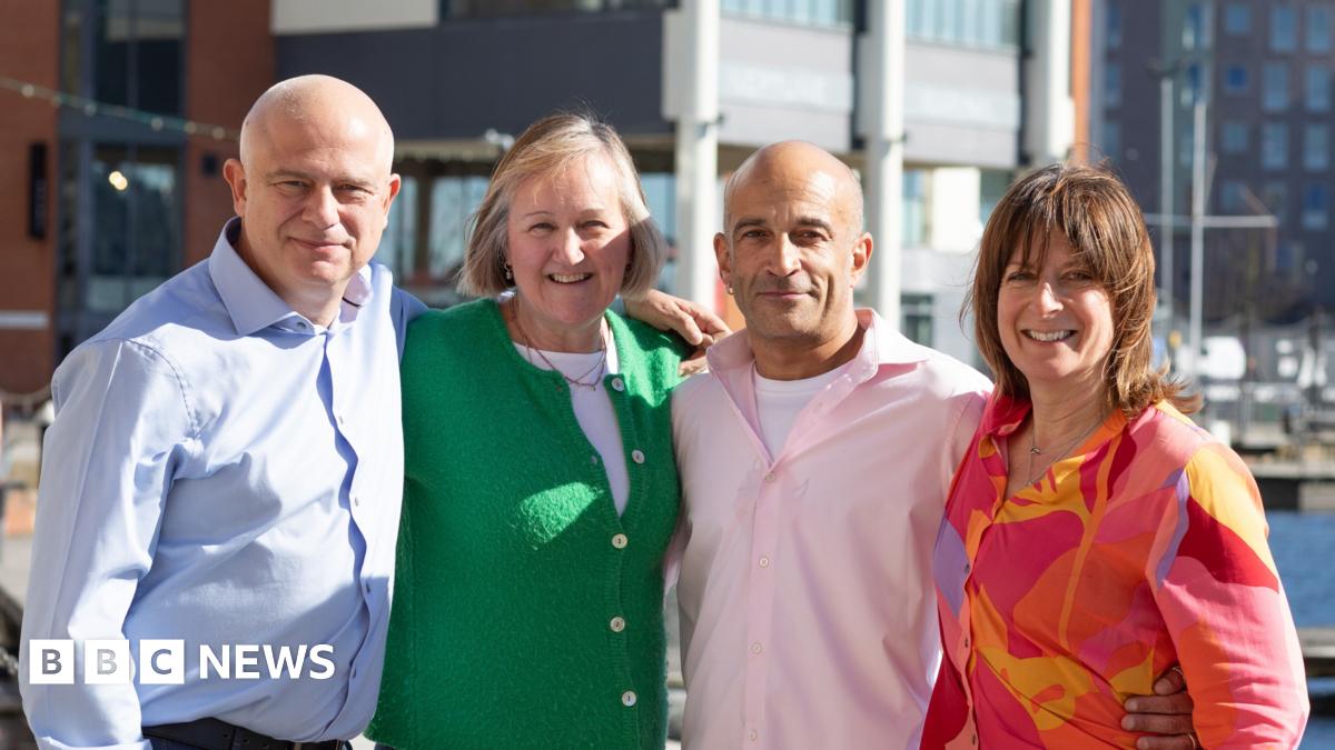Larry Lamb at an art gallery. He has short grey hair, is wearing glasses and a green and black plaid top.