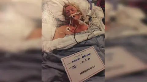 Handout A woman in a hospital bed with lots of tubes strapped to her face. 