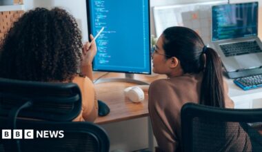 Eddie Hart works at a laptop, surrounded by other young coders at a coding fair.