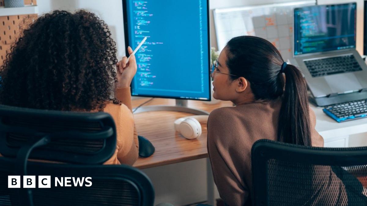 Eddie Hart works at a laptop, surrounded by other young coders at a coding fair.