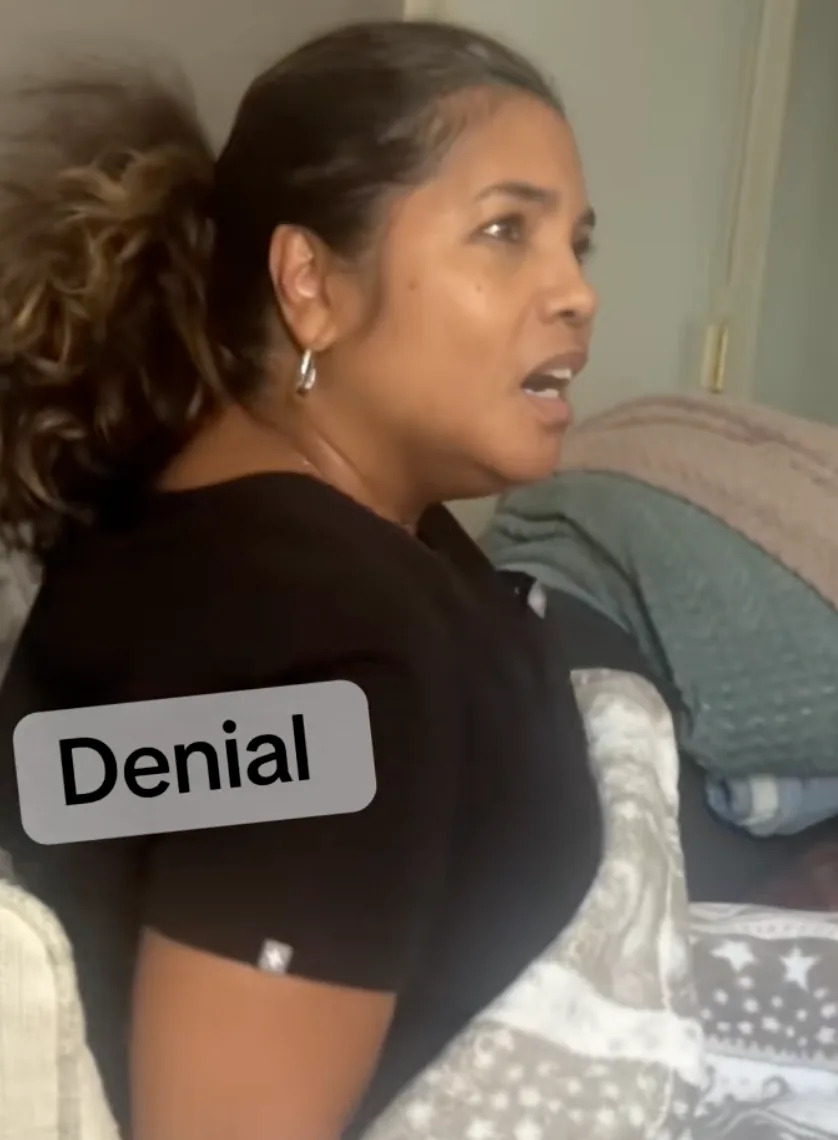 Woman sitting on a couch, looking surprised, with the word "Denial" overlaid on the image