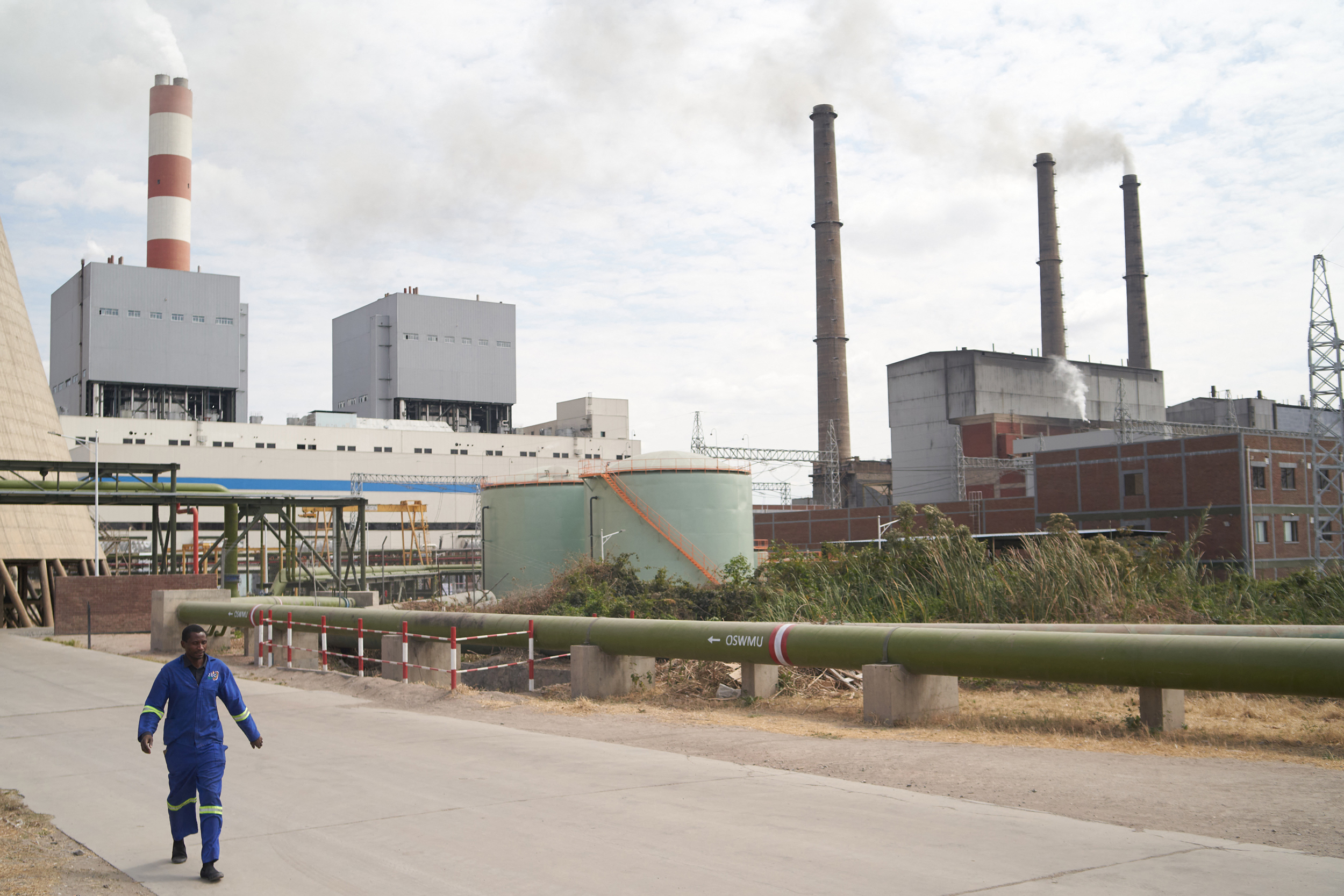 A man walks outside a coal-fired generating plant in Hwange, Zimbabwe. Credit: Zinyange Auntony/AFP via Getty Images