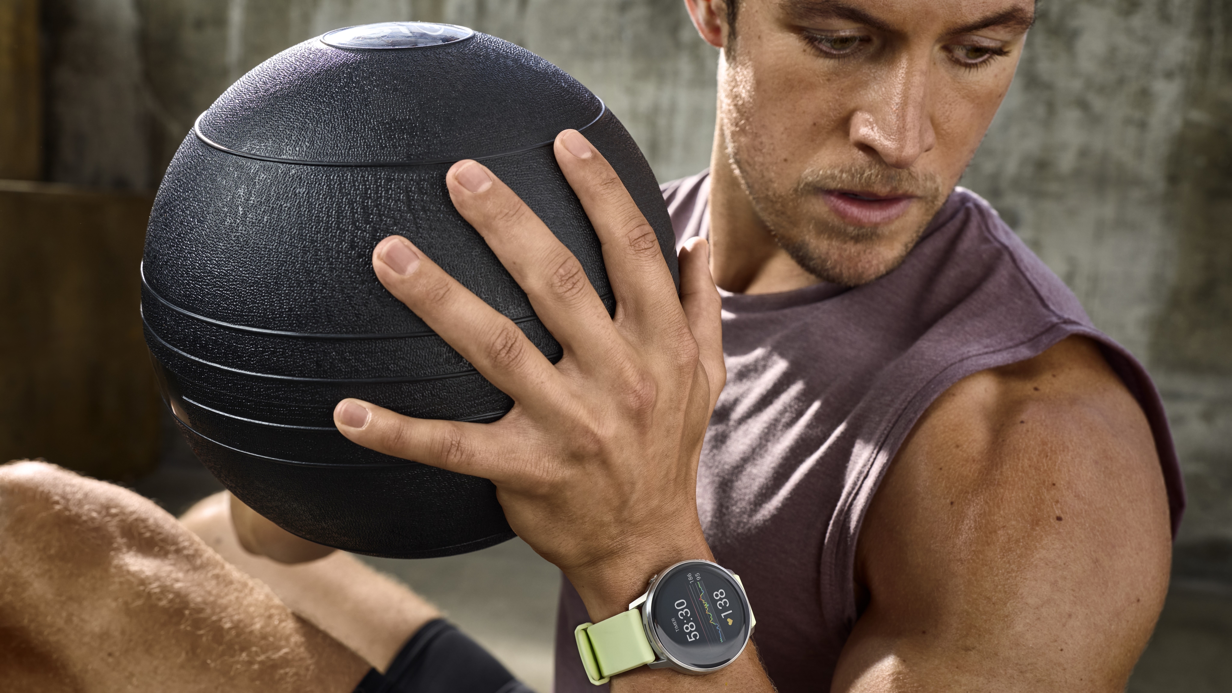 A photo of the Garmin Venu 4 on a man's wrist as he works out with an exercise ball.