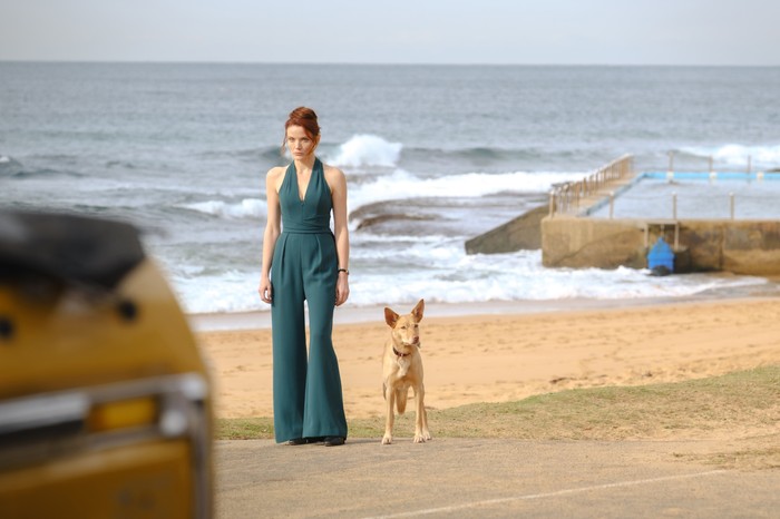 Anna Samson in Return to Paradise. She is stood on a beach next to Frankie the dog.