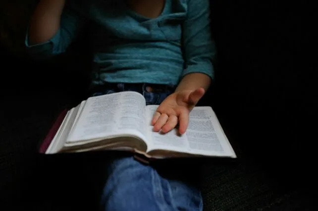 child holding book open
