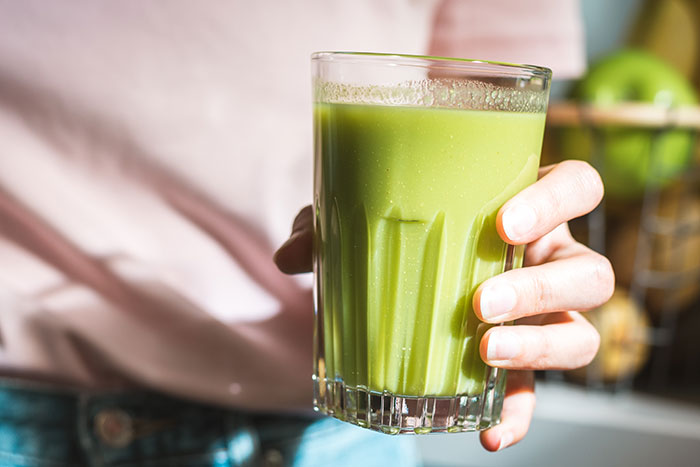Person holding a glass of green juice representing ridiculous cures offered to chronically ill people.