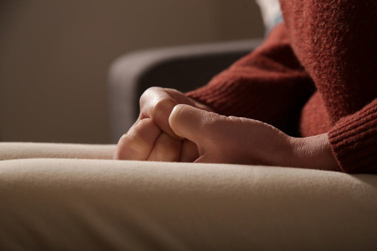 Close-up of person picking at their hands in their lap