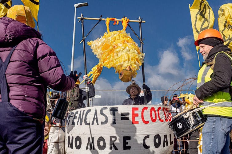 people standing around white protest banner about ecocide