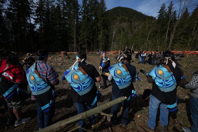 The backs of people seen as someone speaks outdoors.