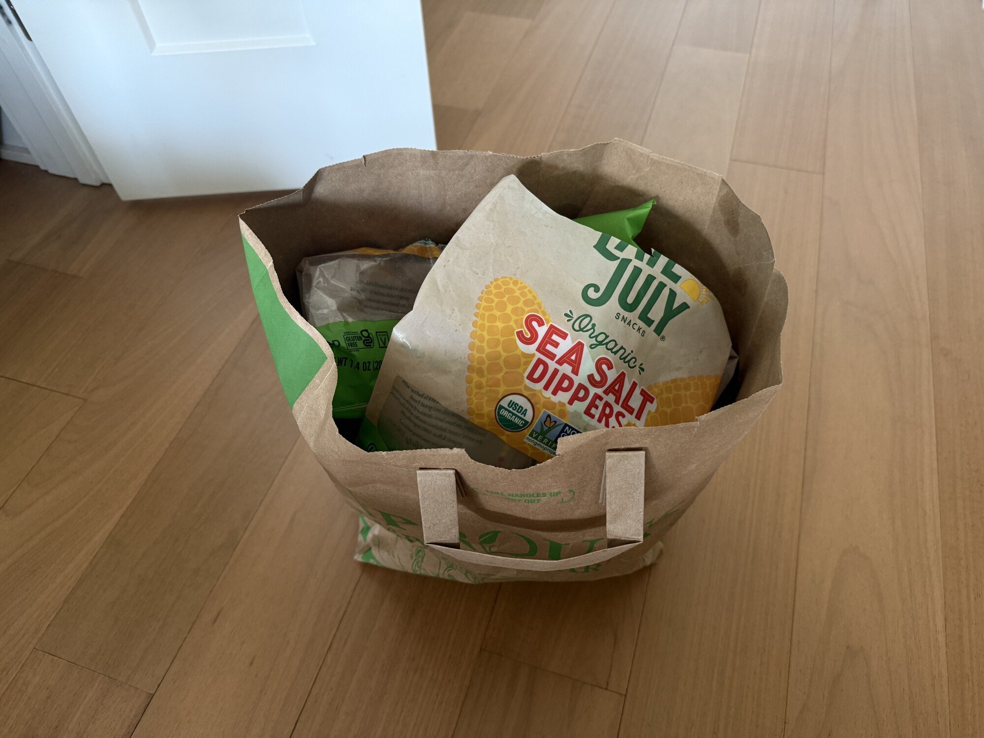 Paper bag filled with tortilla chip bags sitting on floor