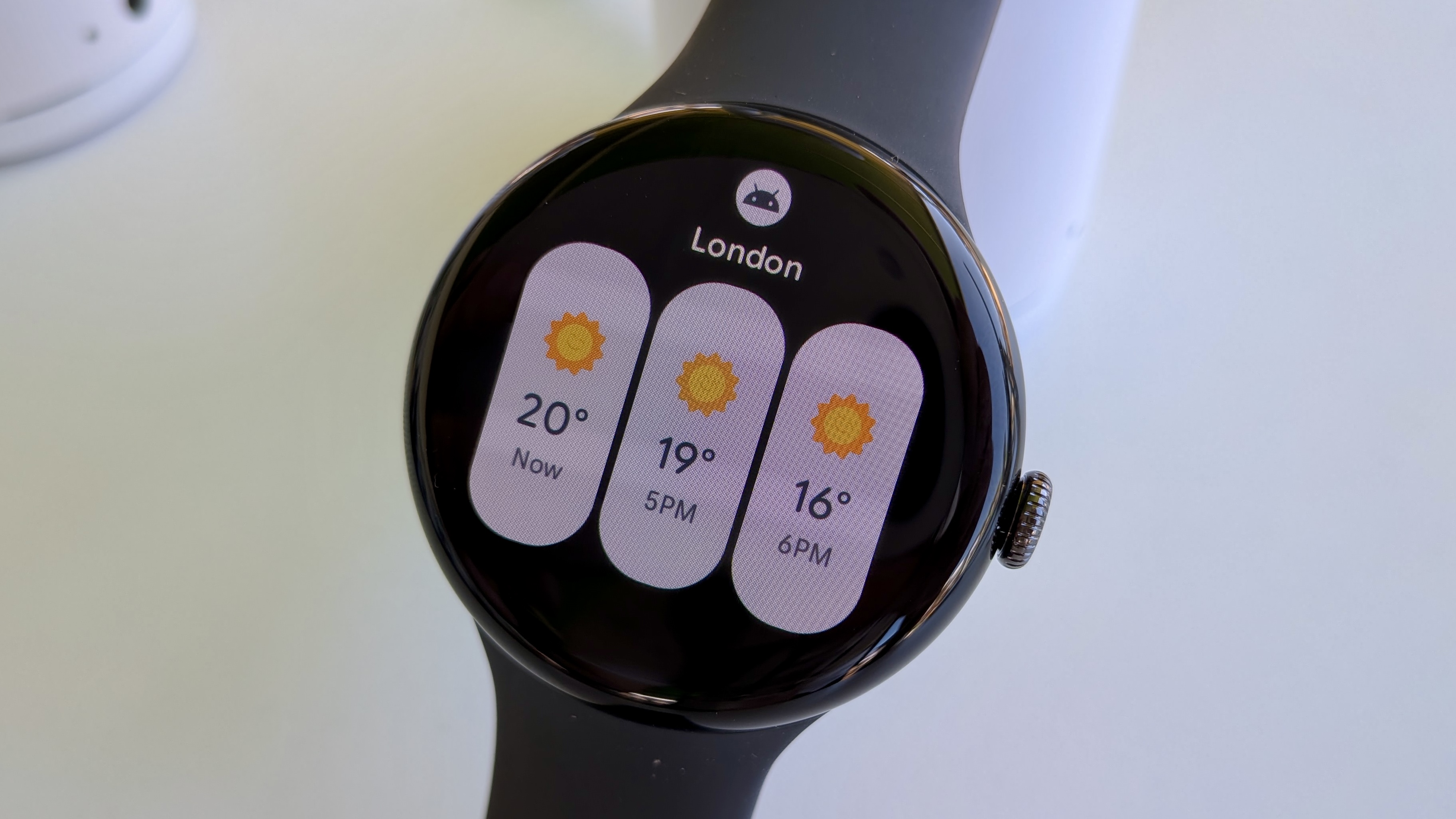 The new Weather tile on Wear OS 6, showing three narrow tiles for Now, 5PM, and 6PM temperatures in London.