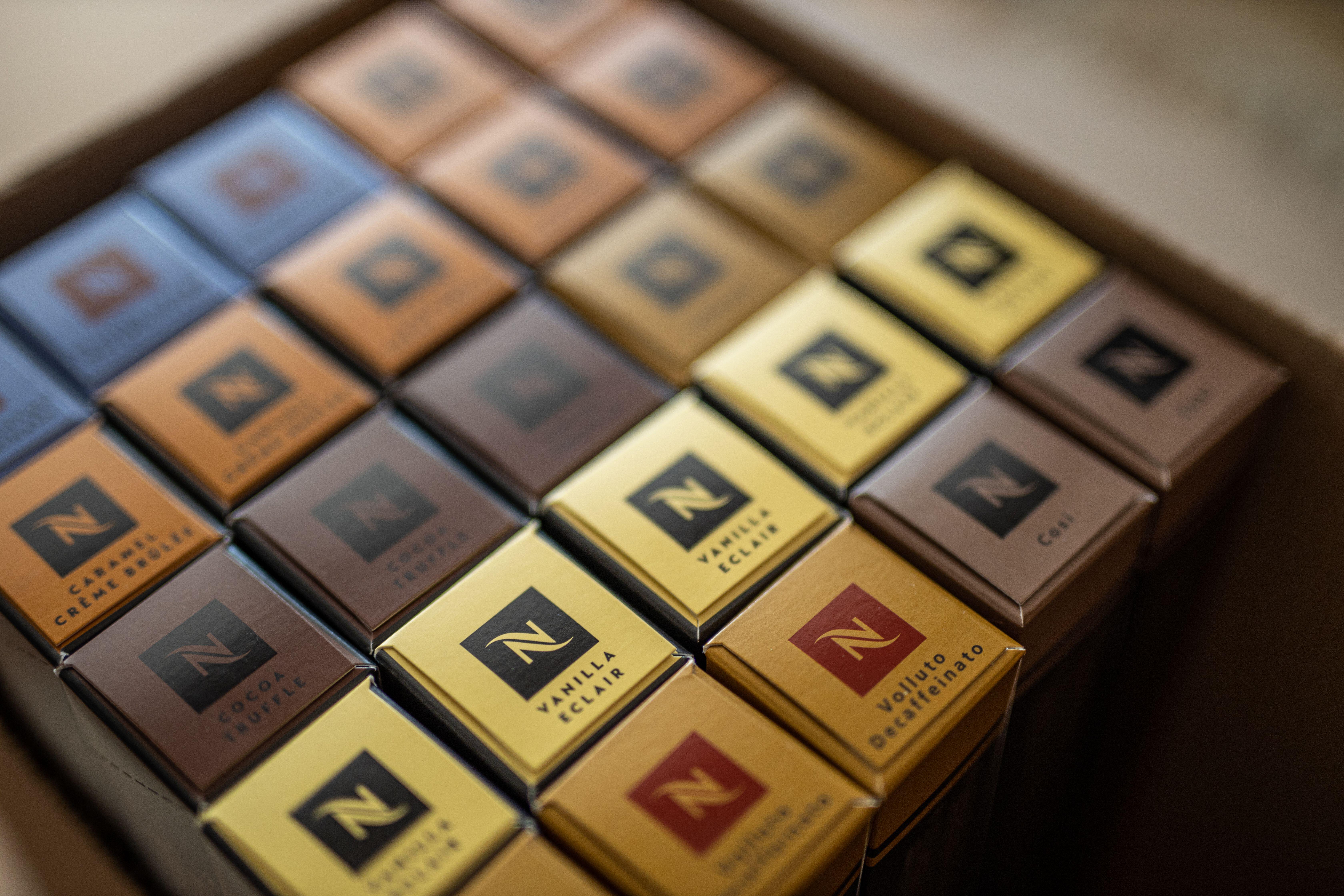 Nespresso coffee capsules in various flavors, including Caramel Crème Brûlée, Cocoa Truffle, Vanilla Eclair, and Volluto Decaffeinato.