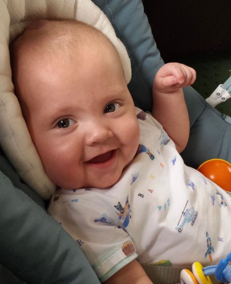 Tommie Denman as a baby, smiling in a baby seat.