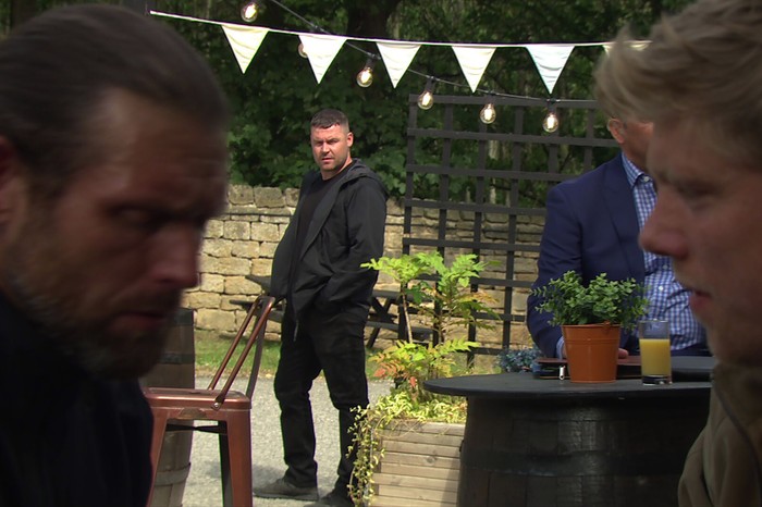 Aaron looking on at Kev and Robert in Emmerdale