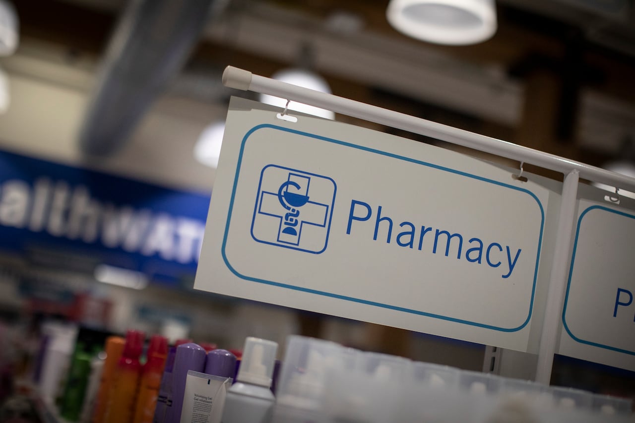 A sign in a hanging over a bunch of products that says pharmacy.