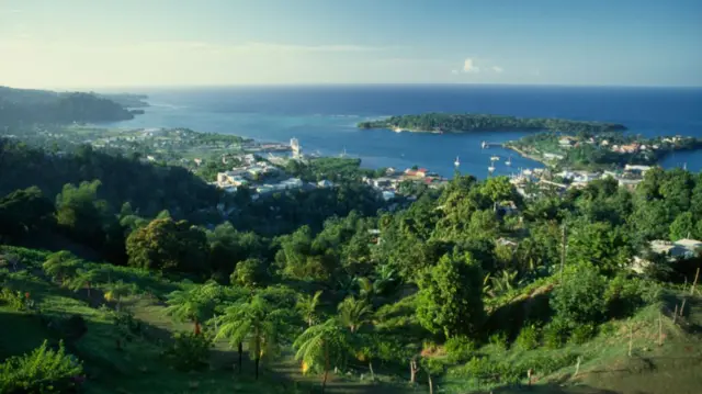 A hilly Jamaican countryside with the coast and a town in the distance