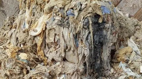 South West Water A fatberg seen with different items such as sanitary products and wet wipes in a huge mass. It is brown and yellow in colour. 