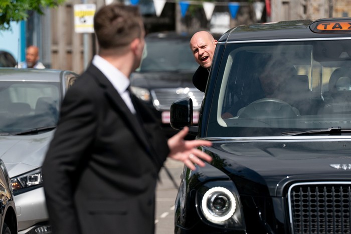 Stuart hanging out of a taxi window calling out to Callum in EastEnders