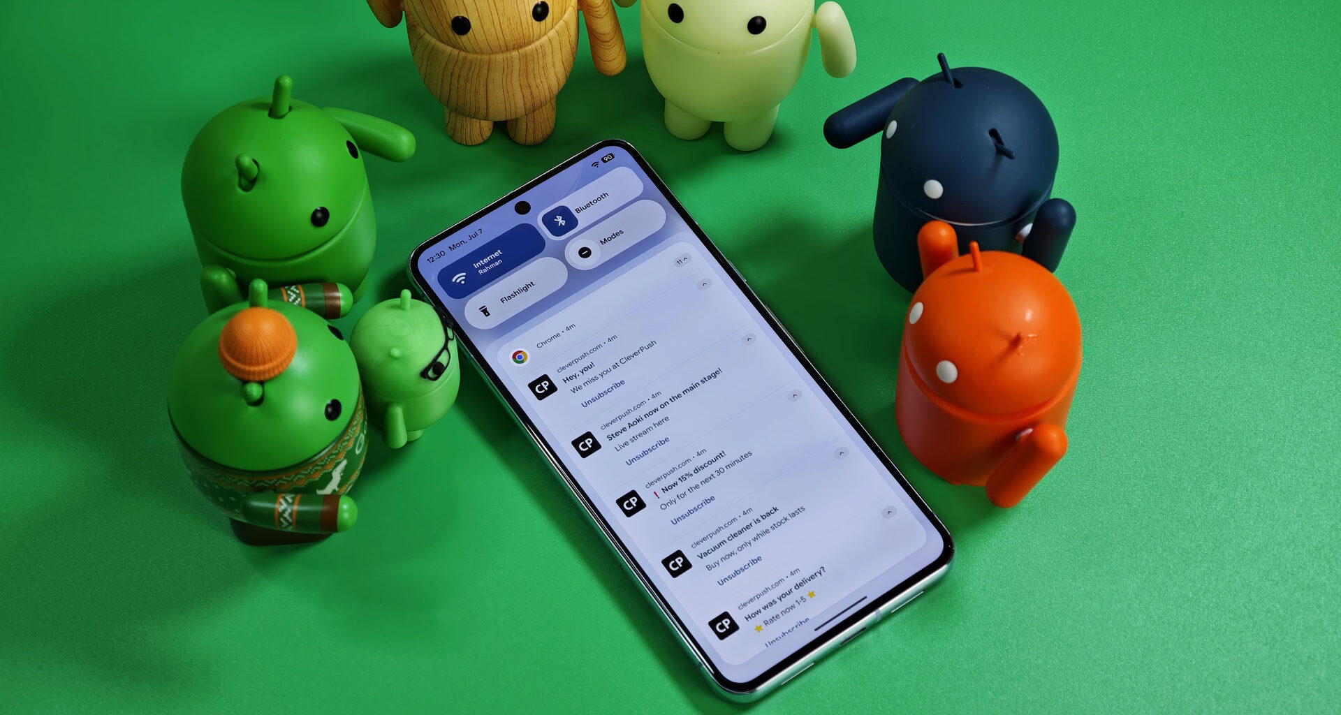Android bots standing over a Pixel phone with various notifications