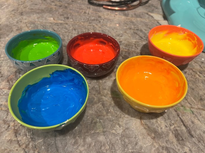 Five small bowls of sprinkle goo, but now dyed green, blue, red, orange, and yellow.