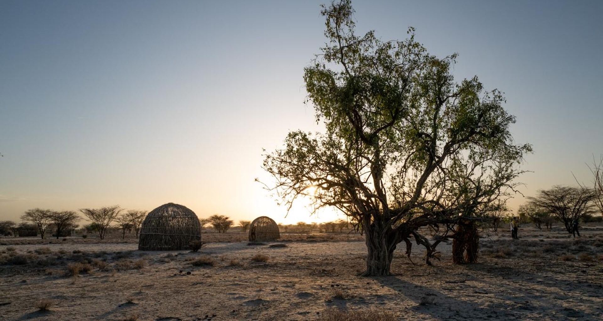 A view of traditional Kenyan housing structures at sunset