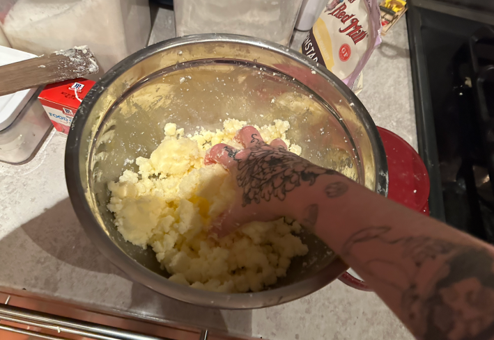 Hand in mixing bowl with sugar and butter