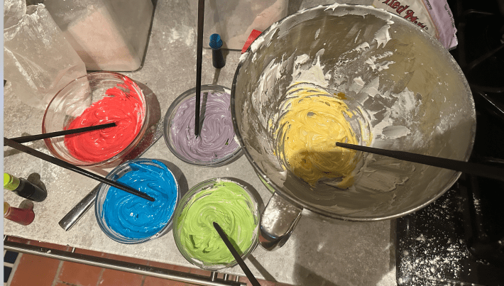 Bowls of colored icing with chopsticks for mixing