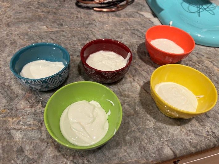 Five small bowls full of white sprinkle goo.