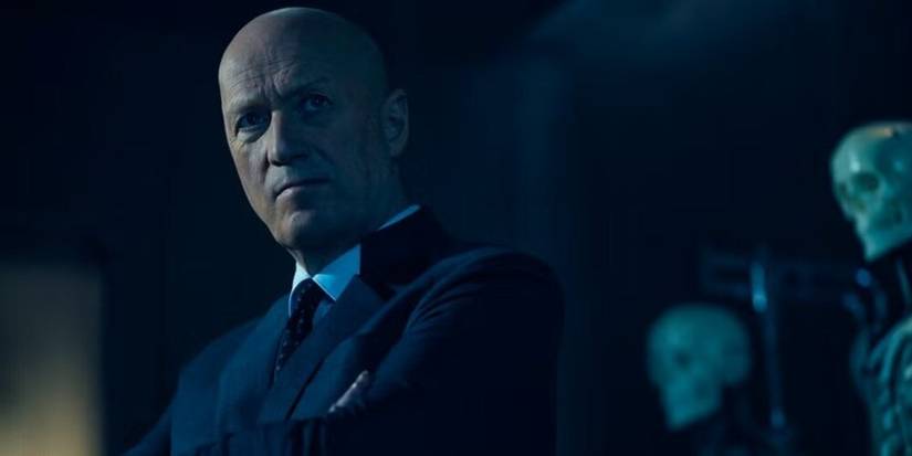 A close-up of Atom Eins standing in front of a few skeletons