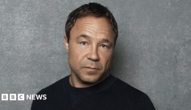 Stephen Graham head and shoulders shot. He is wearing a black top.