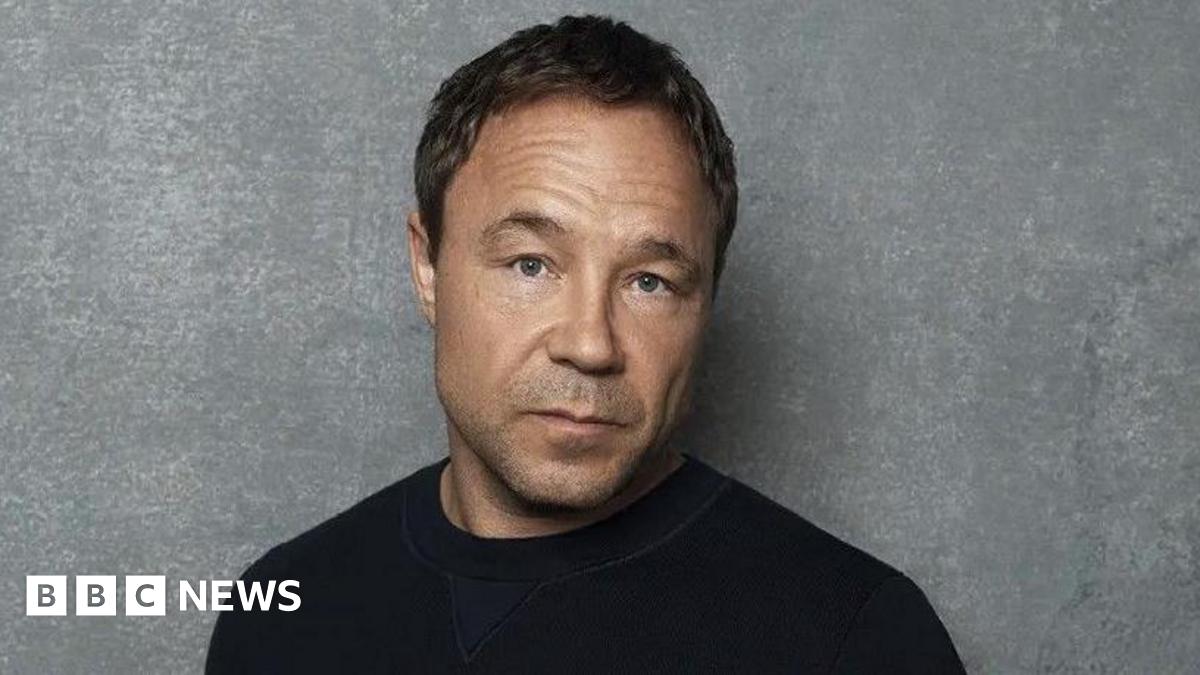 Stephen Graham head and shoulders shot. He is wearing a black top.