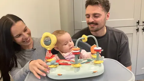 BBC/PHIL BODMER A young couple with their baby in a high chair
