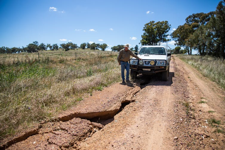 farmer in ute looking at a flood damaged road.