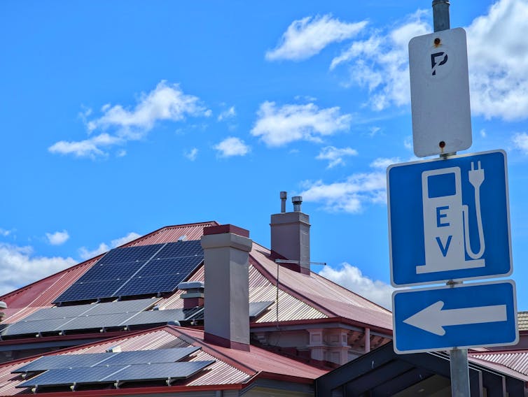 solar panels on roof of a house and a EV charger road sign.