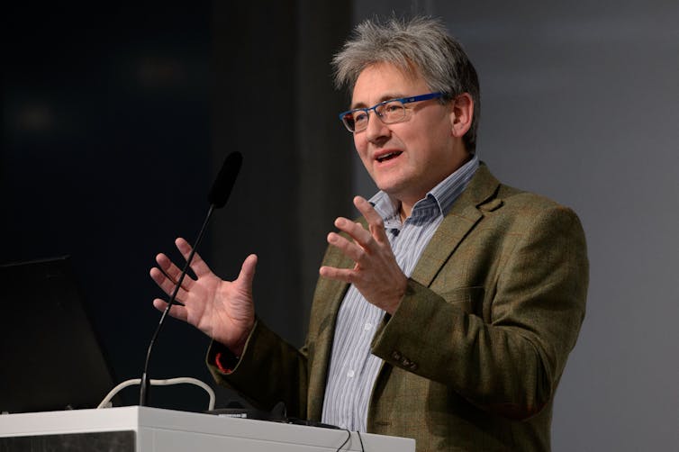 Callum Roberts wearing suit speaking at podium