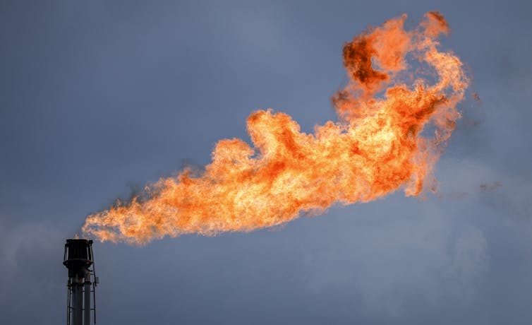 a large flame emerging from the top of a flare stack