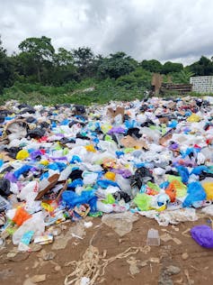 A pile of plastic bags and bottles dumped outside on the ground