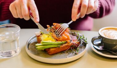 A man's hands cutting a salmon and avocado flatbread with a knife and fork.