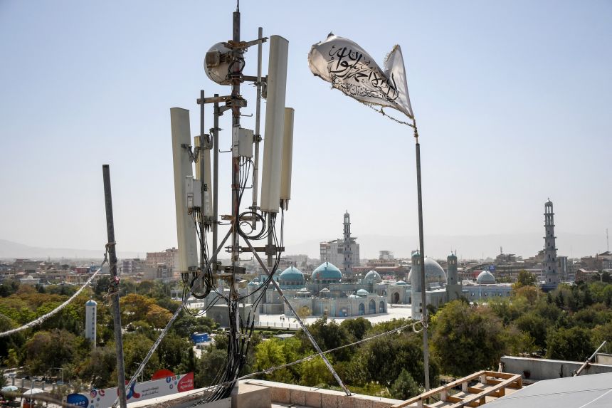 A Taliban flag flutters near telecom equipment overlooking the Hazrat-e-Ali Shrine in Mazar-i-Sharif on September 16, 2025, after the Taliban banned fibre-optic internet in Balkh province.