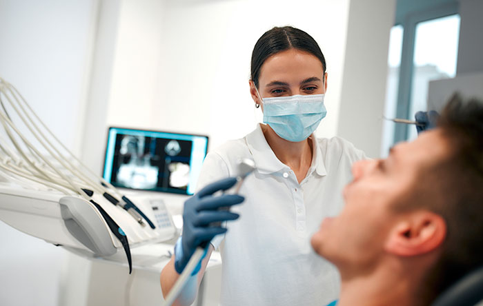 Dentist wearing mask and gloves examining patient in clinic, highlighting common self-diagnosis mistakes by people.