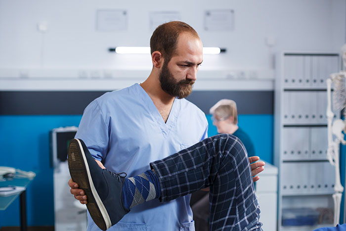 Male doctor examining patient's leg in clinic, illustrating common cases of people self-diagnosing their health issues.