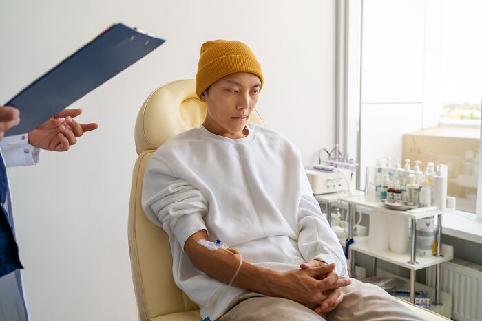 Patient with IV drip sitting in a medical office, appearing worried about symptoms patients often brush off as normal.